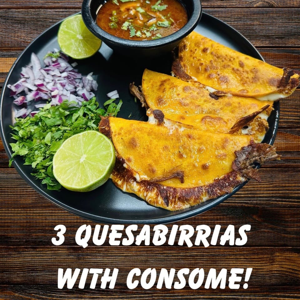 Three quesabirrias with melted cheese, a bowl of consommé, chopped onions, cilantro, and lime wedges.